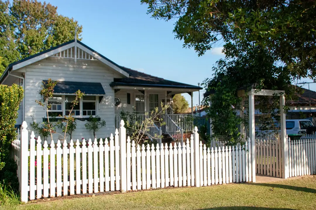 Weatherboard house behind a white picket fence