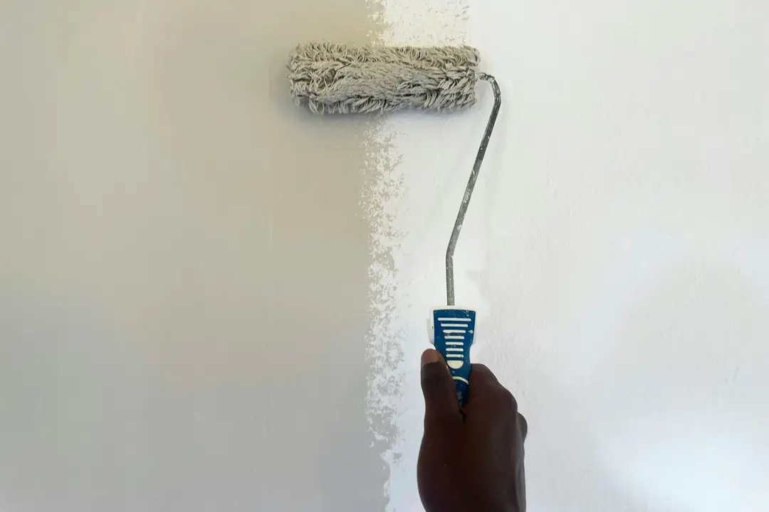 Paint roller applying a fresh white coat to an interior wall